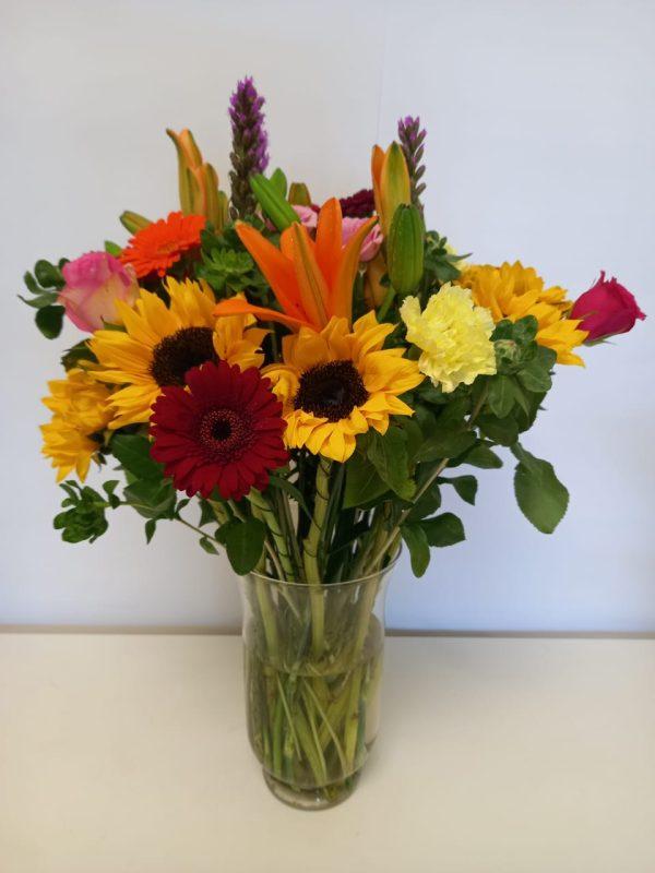 Mixed colourful flowers in a vase babsi george delivery