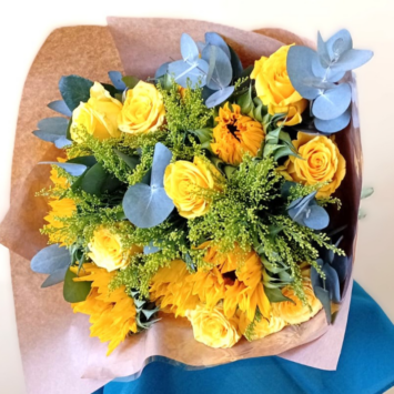 A bouquet of yellow roses and sunflowers with green eucalyptus and foliage