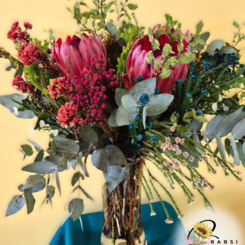 Protea Fynbos arrangement in a clear glass vase with pink ice proteas, filler flowers, colorful accents, eucalyptus and greenery