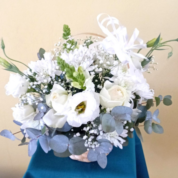 Elegant white sympathy flower basket featuring white roses, gerberas, chrysanthemums, snapdragons and fresh pennygum