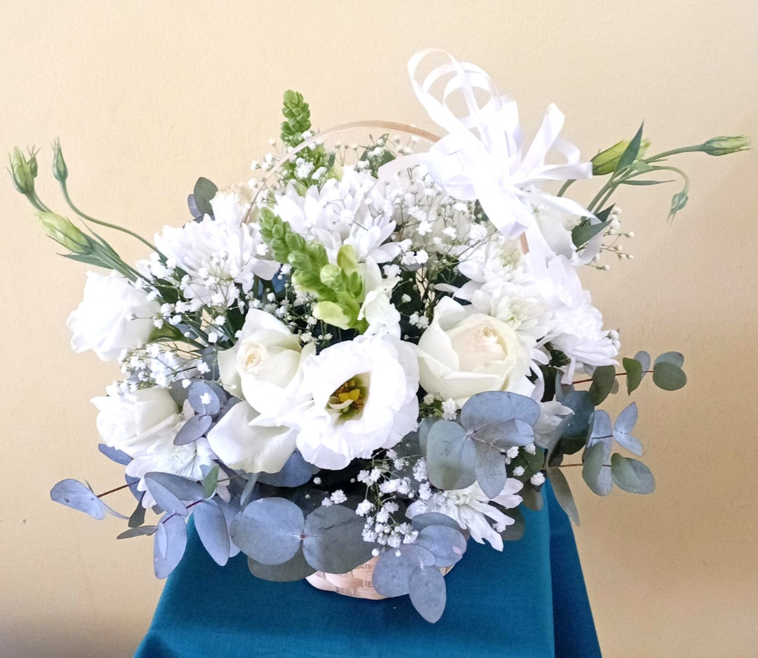 Elegant white sympathy flower basket featuring white roses, gerberas, chrysanthemums, snapdragons and fresh pennygum